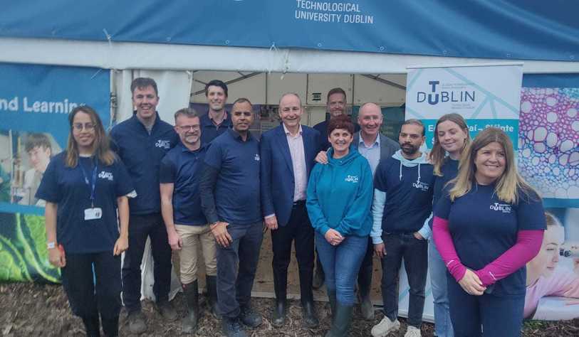 A group of people pose outside a tent with a TU Dublin logo