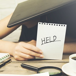 Image of person with laptop on head holding up a page with Help written on it