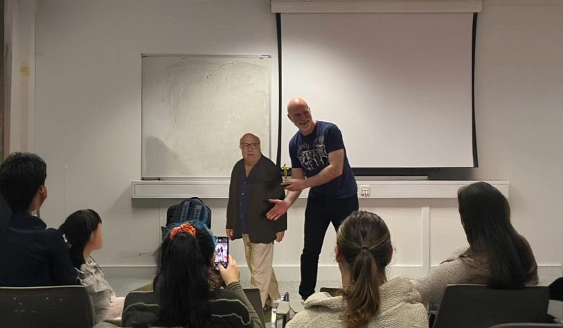 Picture of teacher standing in front of TY students with life size cutout image of Danny DeVito