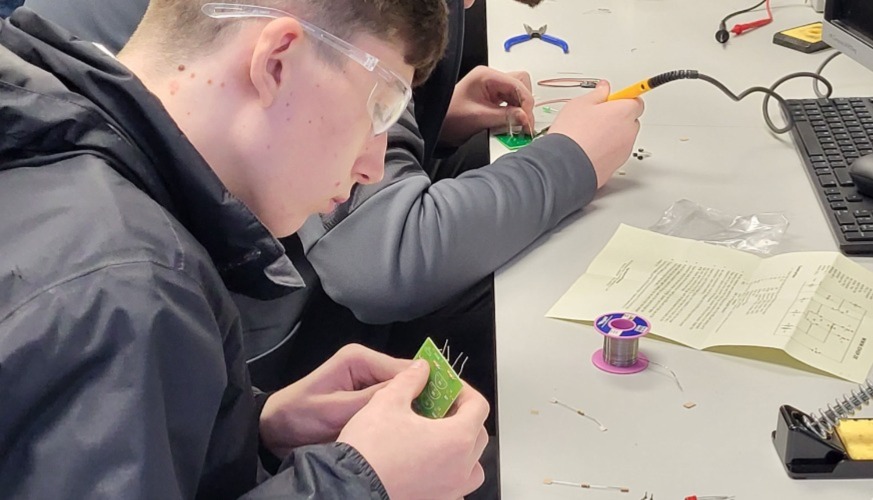 Secondary students with safety glasses working at bench in engineering workshop