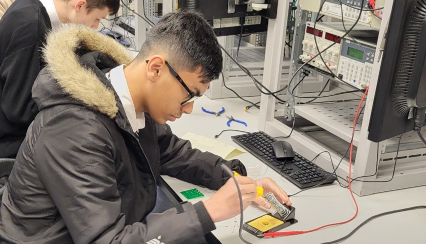 Secondary students with safety glasses working at bench in engineering workshop