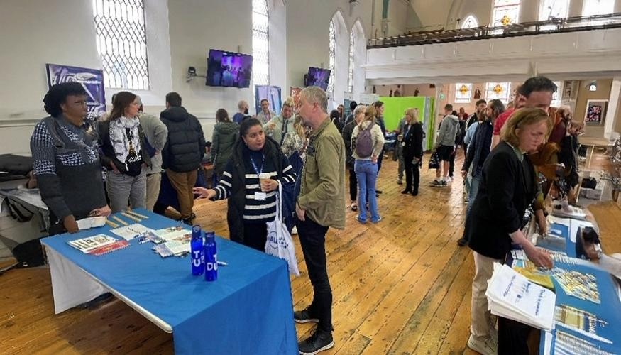 Groups of people gathering and chatting in St Laurence's Church at information morning for Traveller & Roma communities