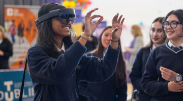 A young girl tries VR goggles surrounded by her friends