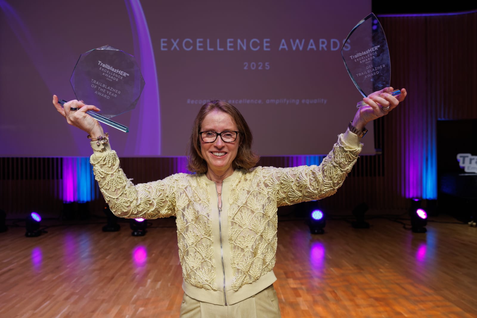 Women in yellow holding up awards