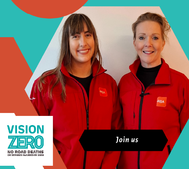 Two white smiling women wearing red RSA promotional jackets with a graphic saying Vision zero in teal, white and orange colours