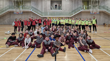 large group of primary school students in a basket ball hall - they are wearing wine coloured uniform
