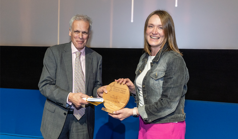 Young white women receiving a student travel award from a grey haired white man.