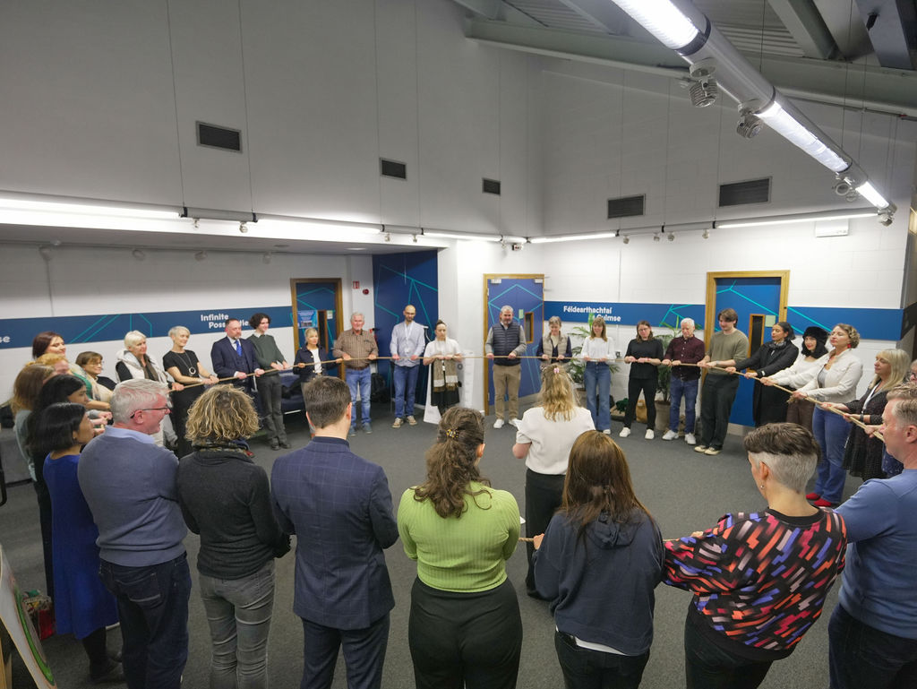 a large group of people holding a rope in a circle