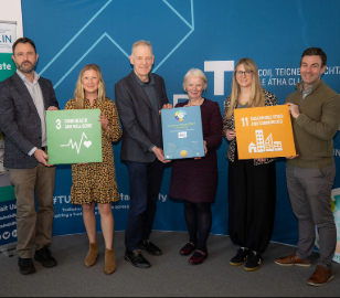 three male and three female hold plaque and sdg signs 11 and 3 against tu dublin backdrop and smile for camera