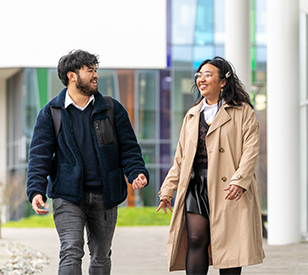 Two students walking on TU Dublins blanchardstown campus with a bright coloured glass backdrop