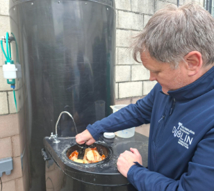 white man pushes food into what looks like a sink inside in a barrel