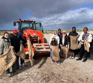 group of people on beach holding hessian bags