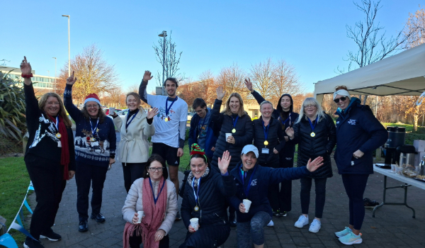 12 women and 2 males smile for camera, all have medals around necks and some have hands in the air