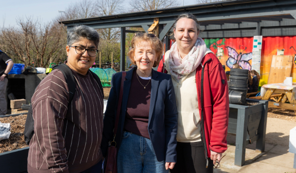 three women smile for camera in outdoor setting