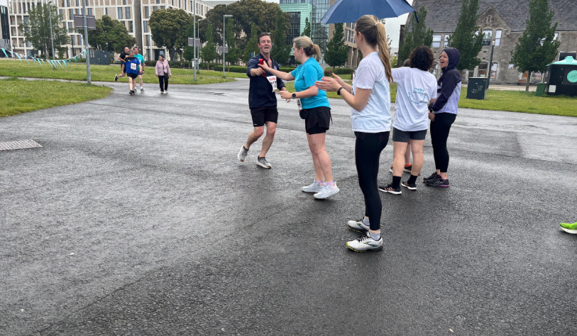 Man passes baton to woman in staff relay race
