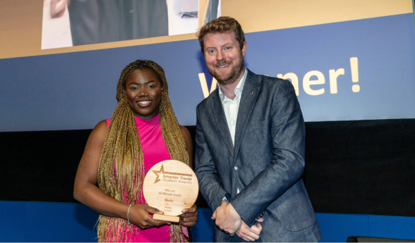 black woman holds award beside white man