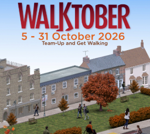 Urban street with 7 people walking, one in wheelchair, trees and hedges are autumnal orange