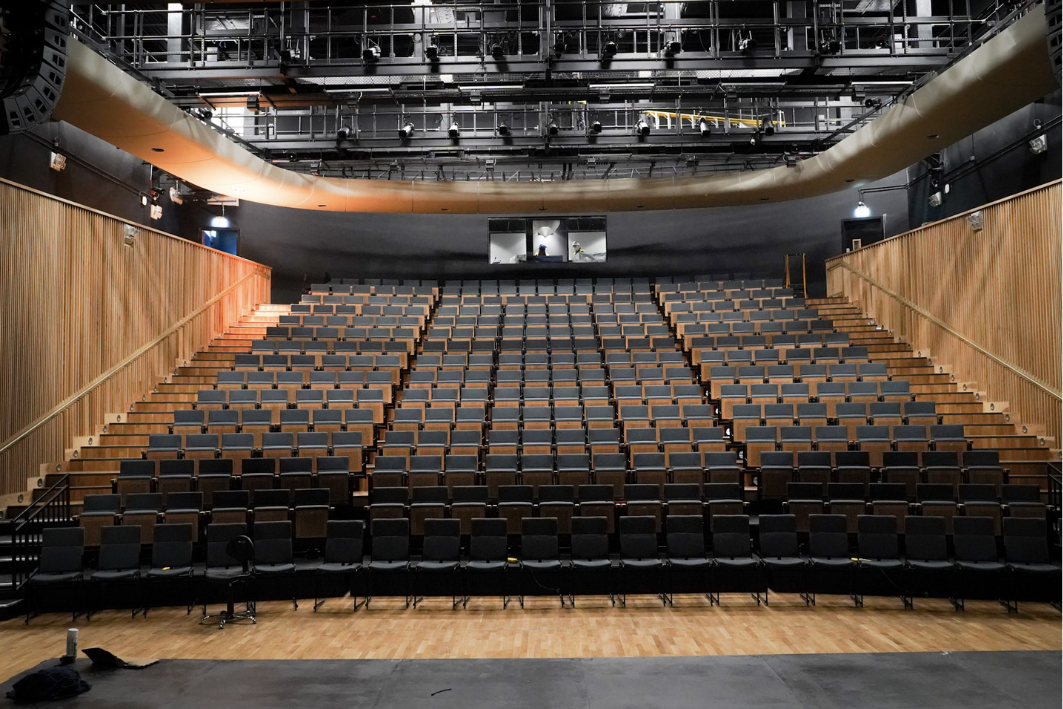 large theatre with tiered seating, a stage at the bottom of the image