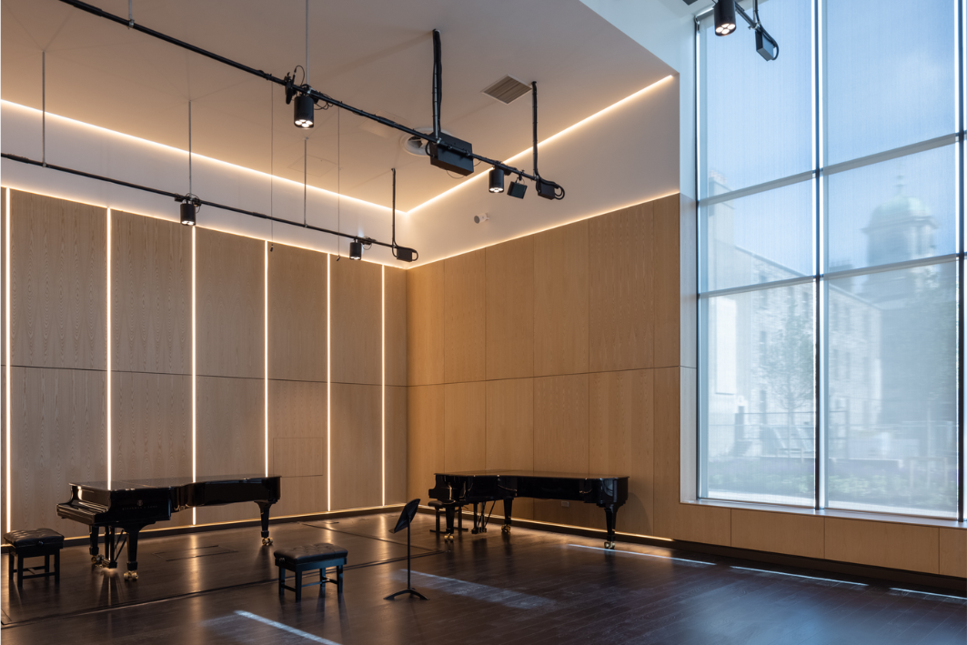 high ceiling room with two pianos and a window