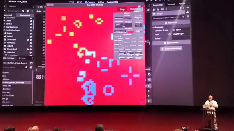 A Person delivering a talk with a very large screen behind them