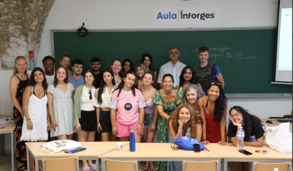 Group photo of smiling students in classroom standing in front of chalkboards