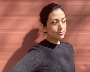 Dr. R Khaled, woman in grey top standing against a wall