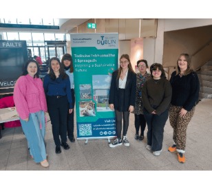 Students posing in front of a poster for the conference