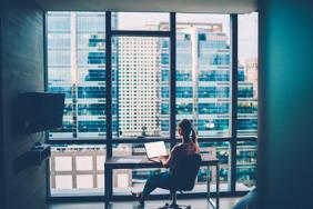 lady sitting at her desk looking out at skyline on her own