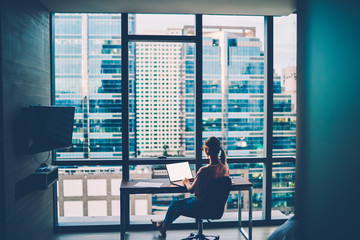lady sitting at her desk looking out at skyline on her own