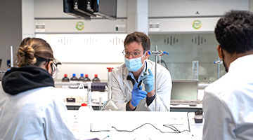 A lecturer working with 2 students in a lab