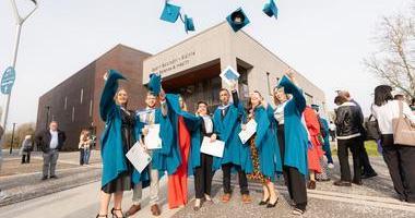 a group of graduates in gowns throw up hats celebrating