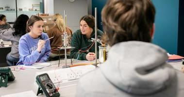 students in research lab studying apparatus