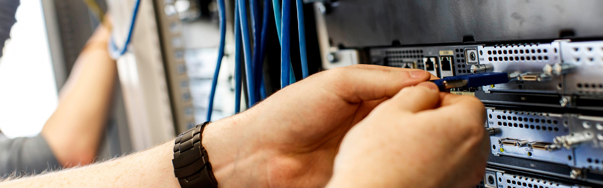 A technician connecting blue network cabling into a server.