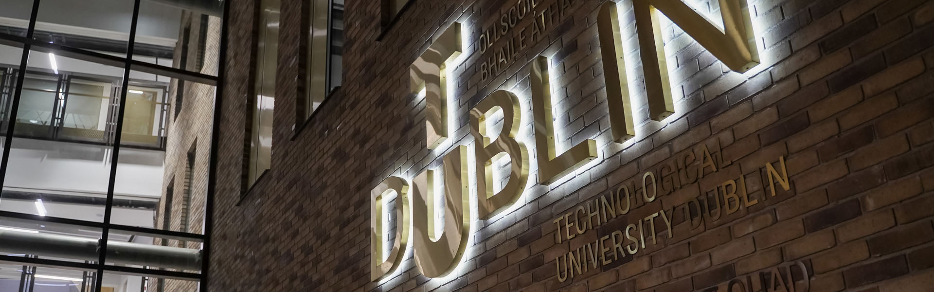 Backlit brass TU Dublin logo at the entrance to the East Quad