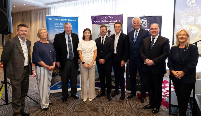 A group of 9 smartly dressed people posing for a photograph at an event