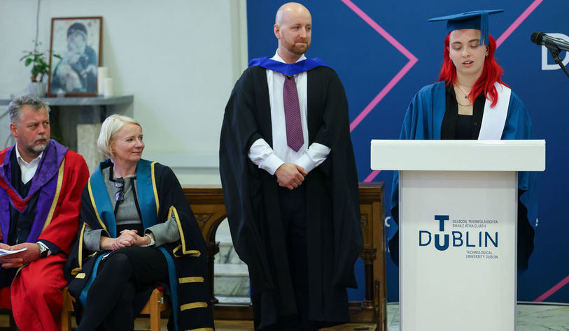 A speaker talks in front of a podium to an audience