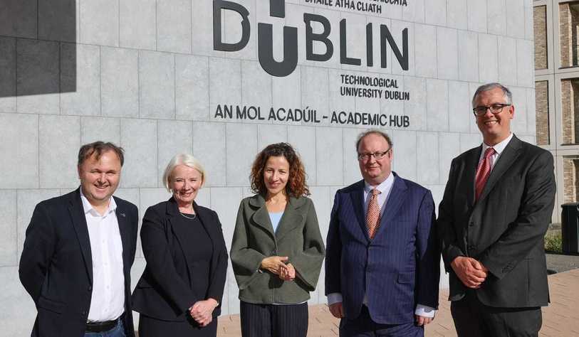 A group of people pose in front of a tu dublin logo