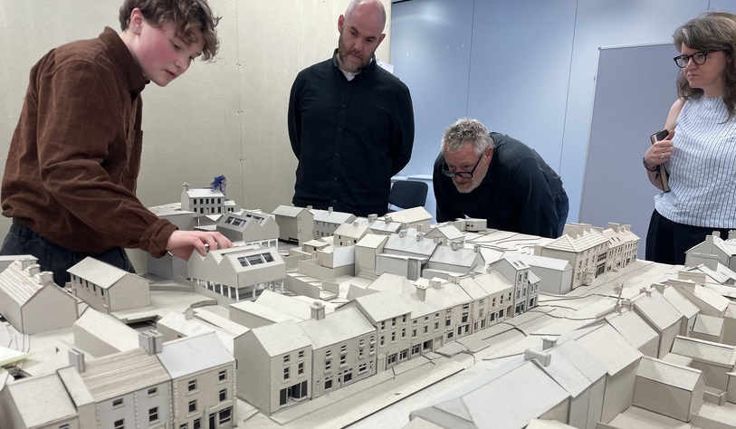 A group of people examine a detailed scale model of Granard town centre, showcasing its streetscape and buildings.