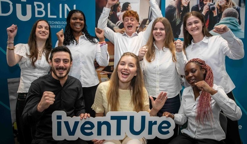 A group of people holding an Iventure sign and cheering
