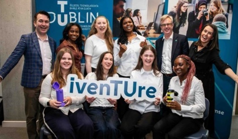 A group of people holding an Iventure sign and cheering