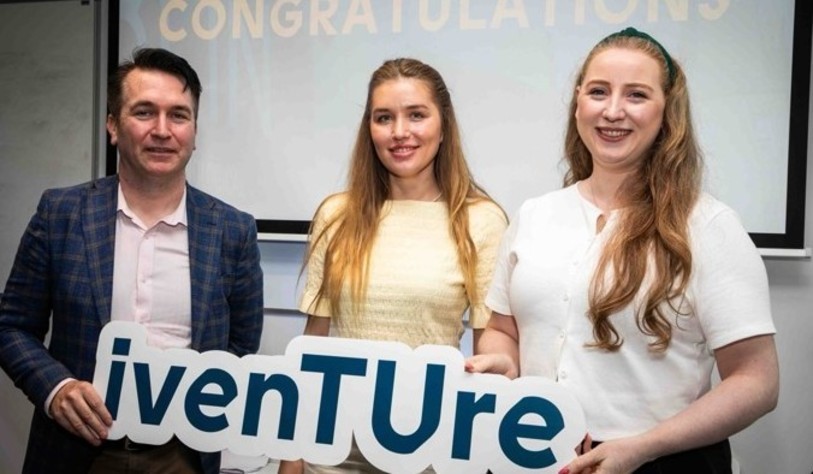 A group of people holding an Iventure sign and cheering
