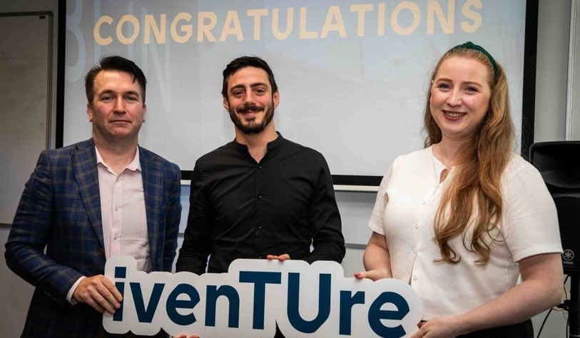 A group of people holding an Iventure sign and cheering