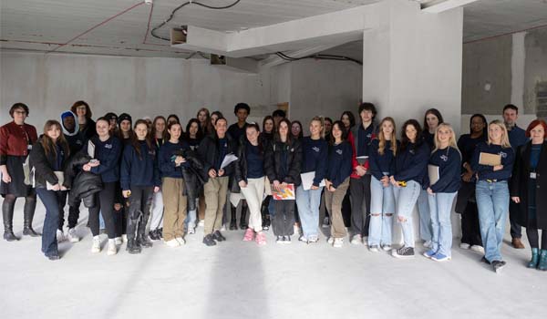 A group of students and staff in a dark unfurnished room