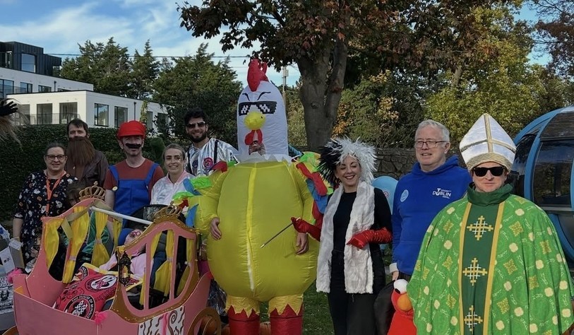 Staff and participants gather outdoors with their imaginative Halloween costumes and homemade parade vehicles.
