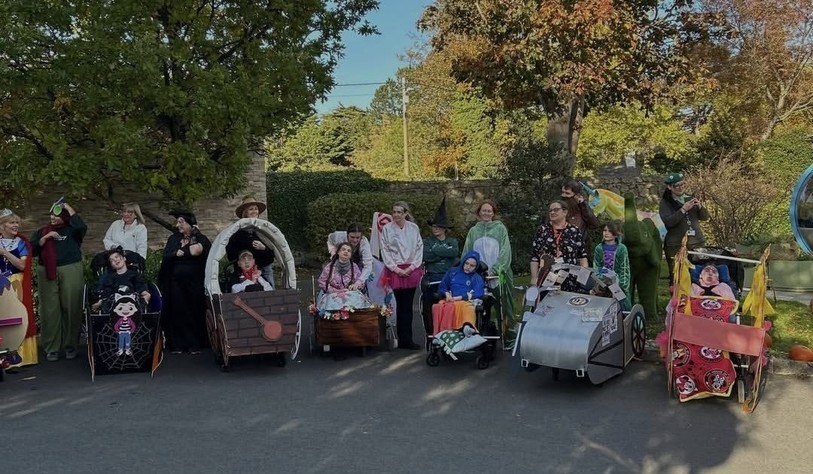 Staff and participants gather outdoors with their imaginative Halloween costumes and homemade parade vehicles.