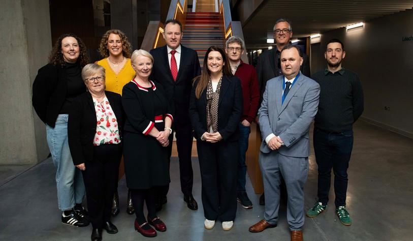 A group of people pose for a photo in front of a large staircase