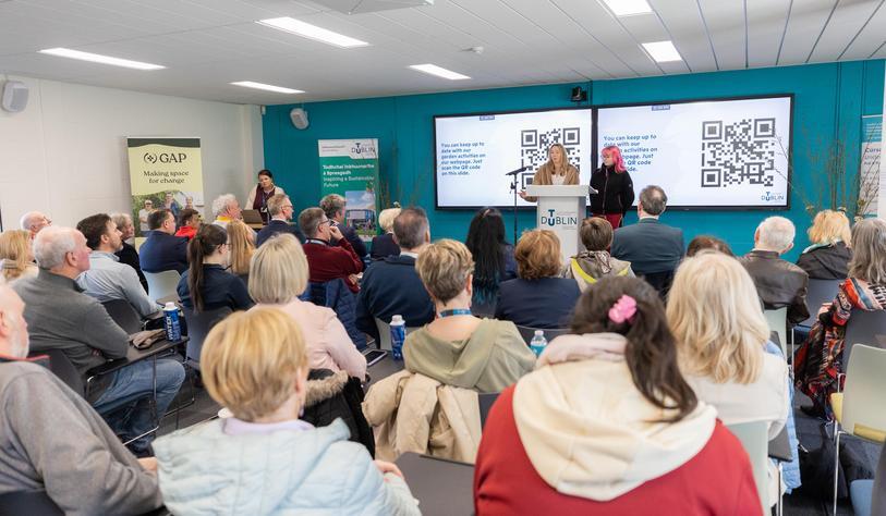 A room of people listen to a speaker at an event