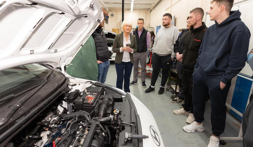 A group stand in front of cars in a mechanical workshop