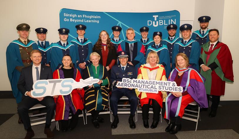 Group photograph of aviation and aeronautical studies graduates, university representatives and guests posing together in academic robes at Technological University Dublin. A sign identifies the BSc Management & Aeronautical Studies programme.