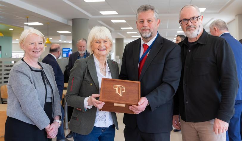A group pf people pose with a wooden handcrafted box